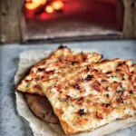 Delicious homemade Flammkuchen topped with cream, onions, and bacon.