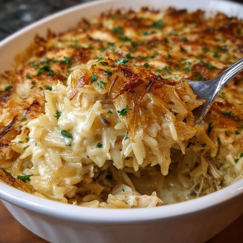 A serving of French Onion Chicken Orzo Casserole topped with cheese.