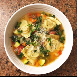 A bowl of delicious ravioli and vegetable soup with herbs and spices.
