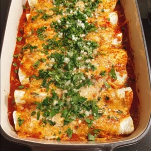 Plate of spicy chicken enchiladas topped with fresh cilantro and cheese
