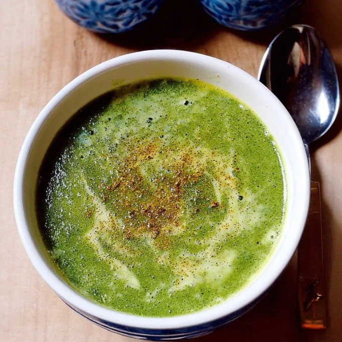 Bowl of spinach soup with cumin garnished with fresh herbs