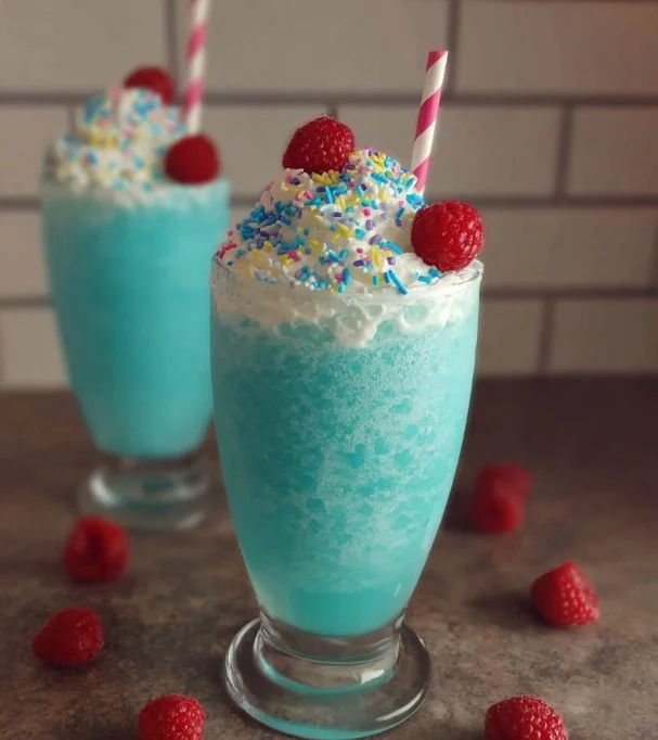 Refreshing Coconut Blue Raspberry Slushie in a glass with ice and garnish