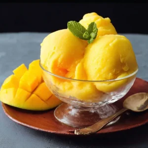Refreshing mango sorbet served in a bowl with fresh mango slices on the side