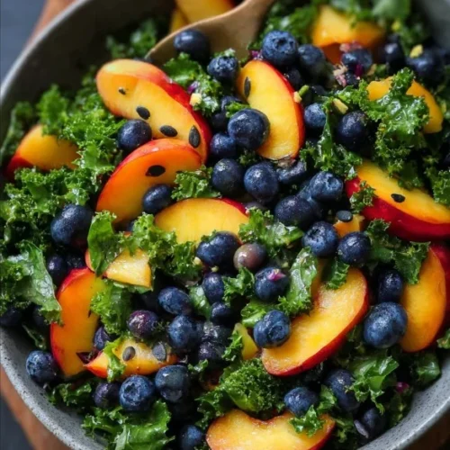 Delicious summer kale salad topped with fresh peaches and blueberries.