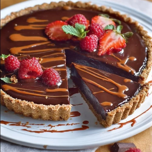 Delicious no-bake chocolate tart topped with chocolate drizzles and berries
