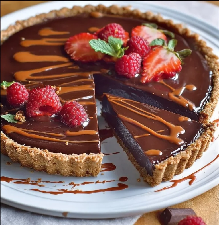 Delicious no-bake chocolate tart topped with chocolate drizzles and berries