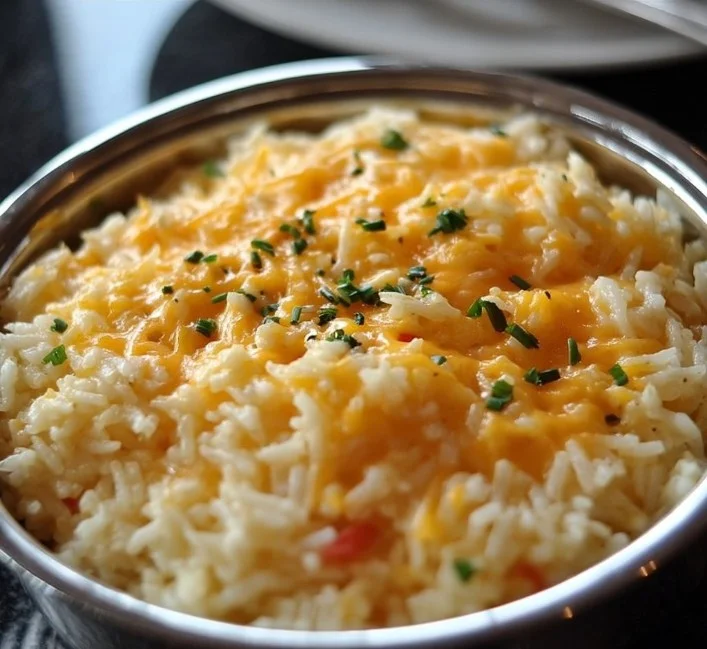 Bowl of cheesy rice with melted cheese and herbs