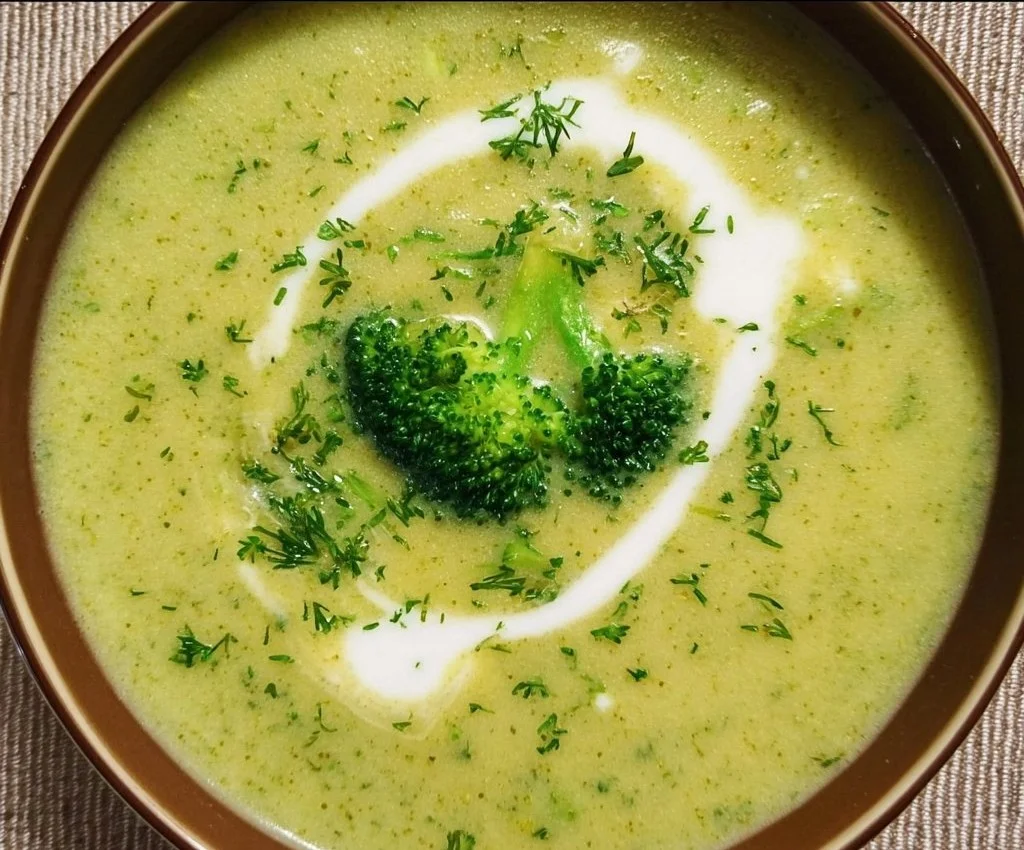 Bowl of creamy broccoli soup with potatoes and cream, garnished with herbs