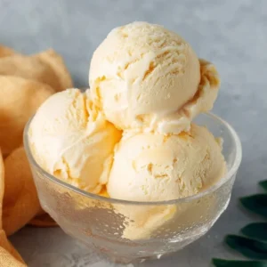Delicious creamy mango ice cream in a bowl with fresh mango slices.