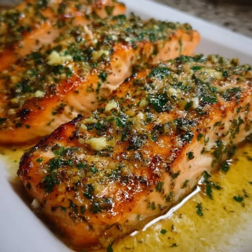 Delicious garlic butter baked salmon garnished with herbs on a plate.
