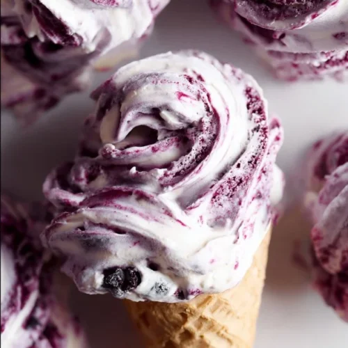 Delicious huckleberry swirl ice cream in a cone with fresh huckleberries