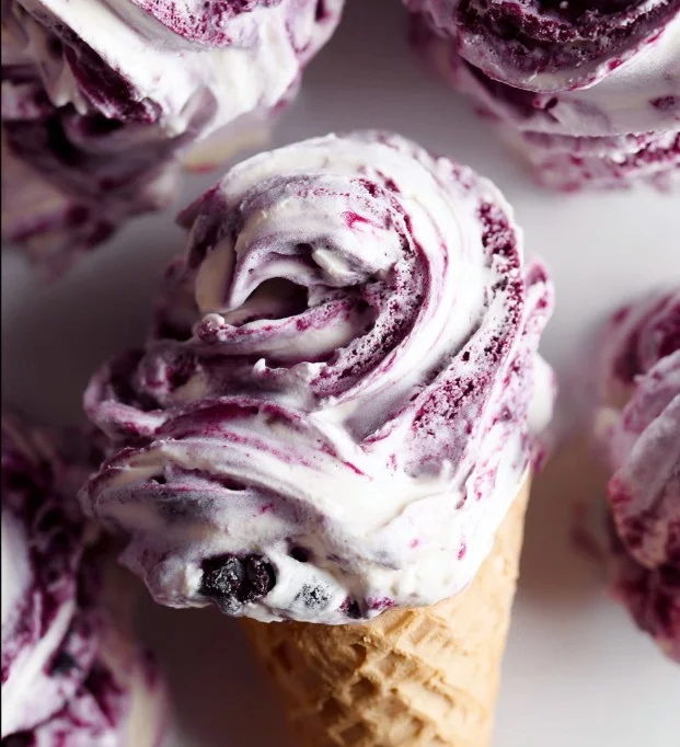 Delicious huckleberry swirl ice cream in a cone with fresh huckleberries