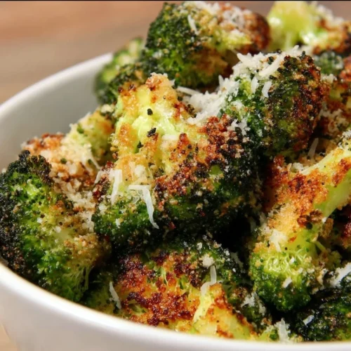 Parmesan Crusted Broccoli Baked Parmesan Crusted Broccoli garnished with seasoning in a serving dish