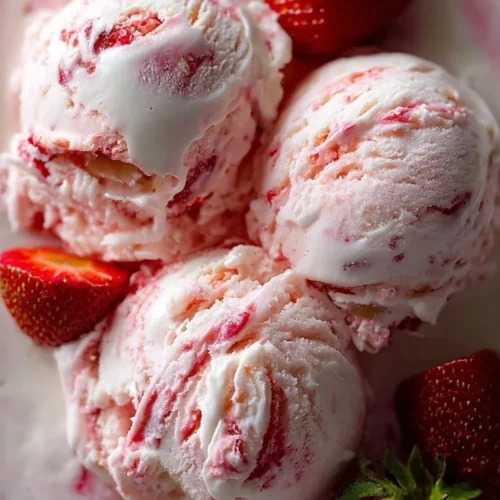 Strawberry Shortcake Ice Cream A bowl of Strawberry Shortcake Ice Cream topped with fresh strawberries and whipped cream.