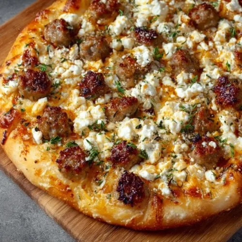 Hot Sausage Feta Honey Pizza topped with fresh herbs and drizzled with honey.