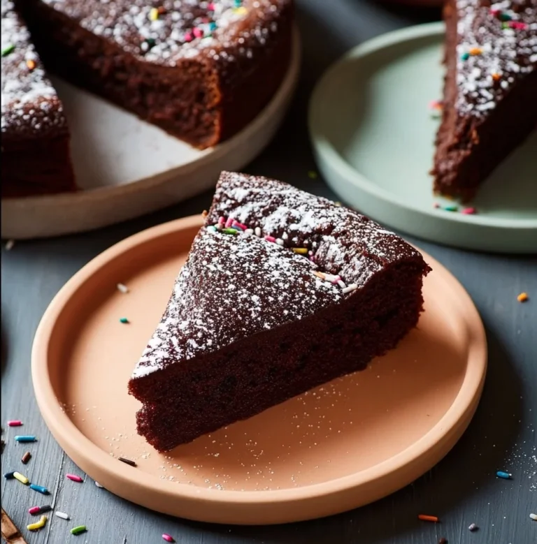A slice of rich chocolate ricotta cake on a plate with sprinkles.